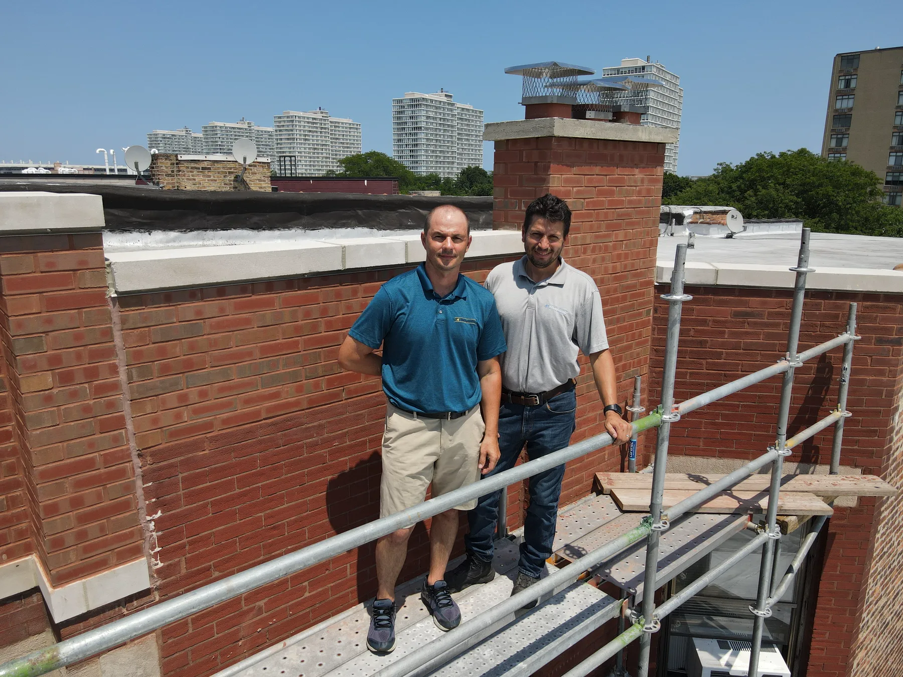 Star Tuckpointing team on a rooftop beside a brick chimney