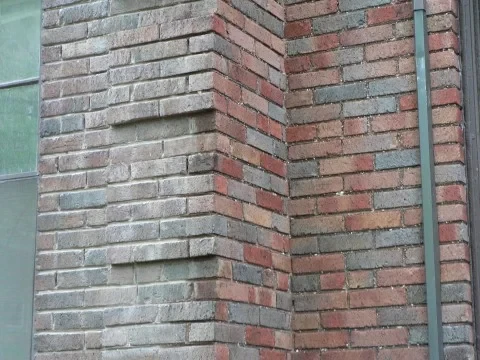 Chicago brick wall corner mid-tuckpointing, showing freshly repointed joints on one side and original weathered mortar on the other