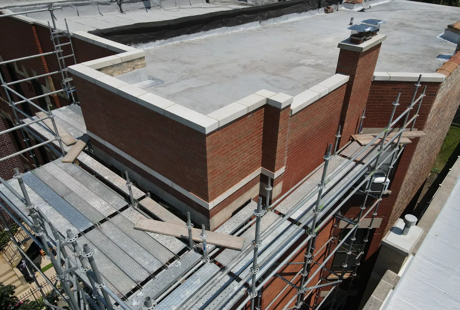 Completed brick parapet repair photographed from above with scaffolding around the building