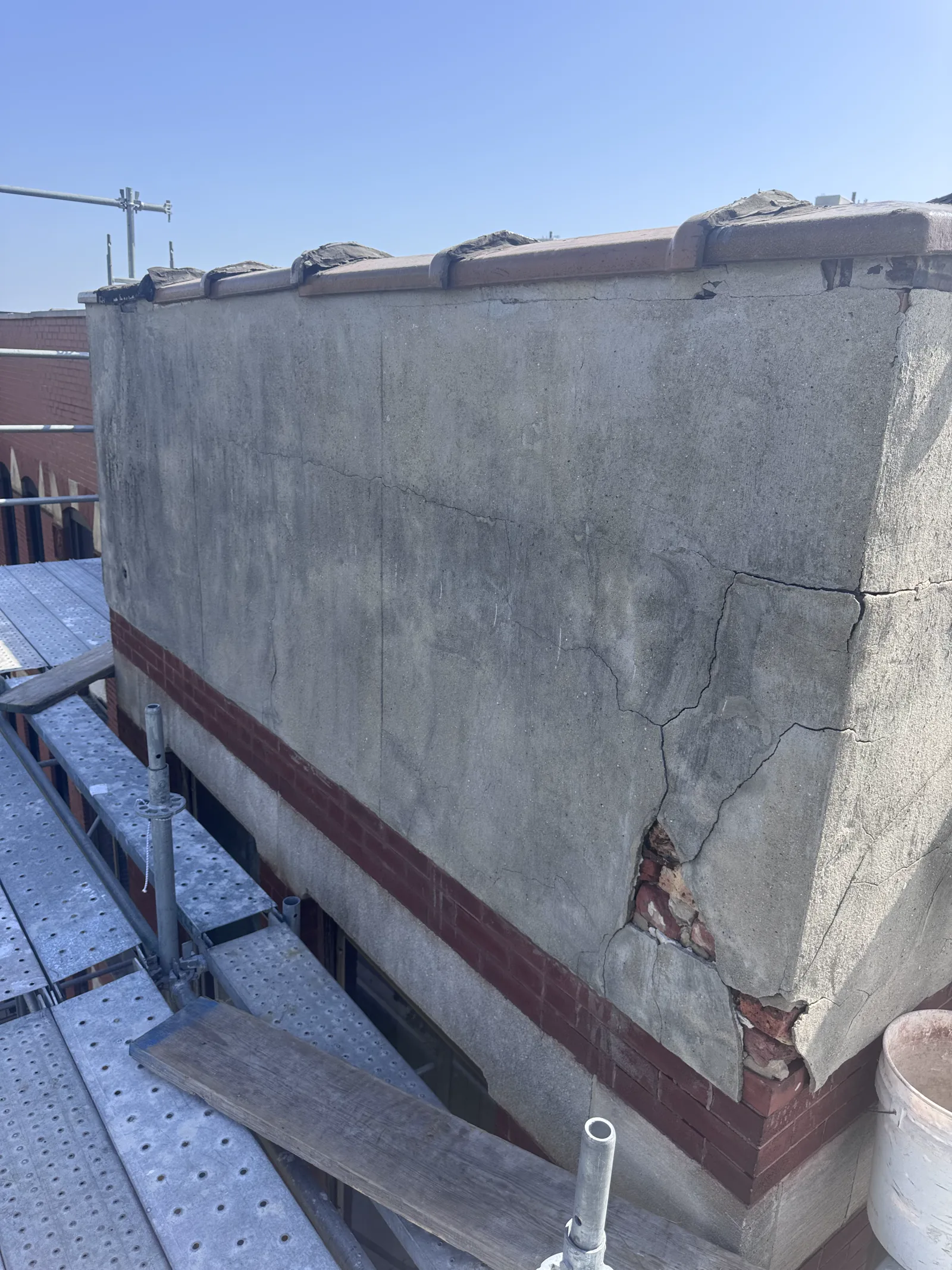Close view of a deteriorated parapet wall and exposed brick from scaffolding before masonry repair