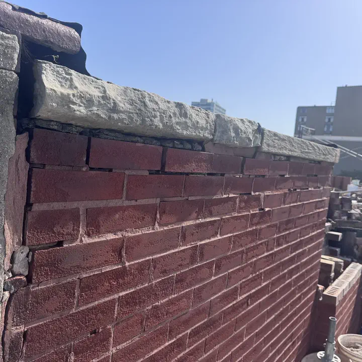 Weathered brick parapet with failing stone coping and exposed mortar joints on a Chicago building — Star Tuckpointing