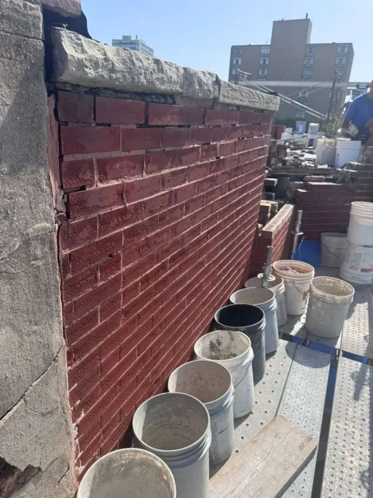 Parapet wall before reconstruction, showing damaged masonry and a leaning upper wall