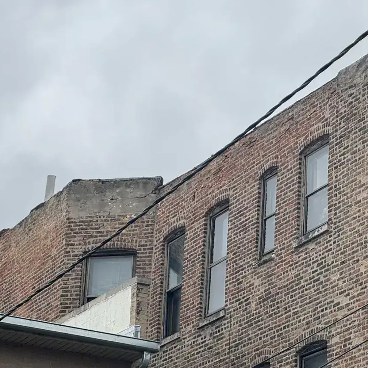 Chicago brick facade suffering from wind-driven rain saturation on both wall faces — Star Tuckpointing
