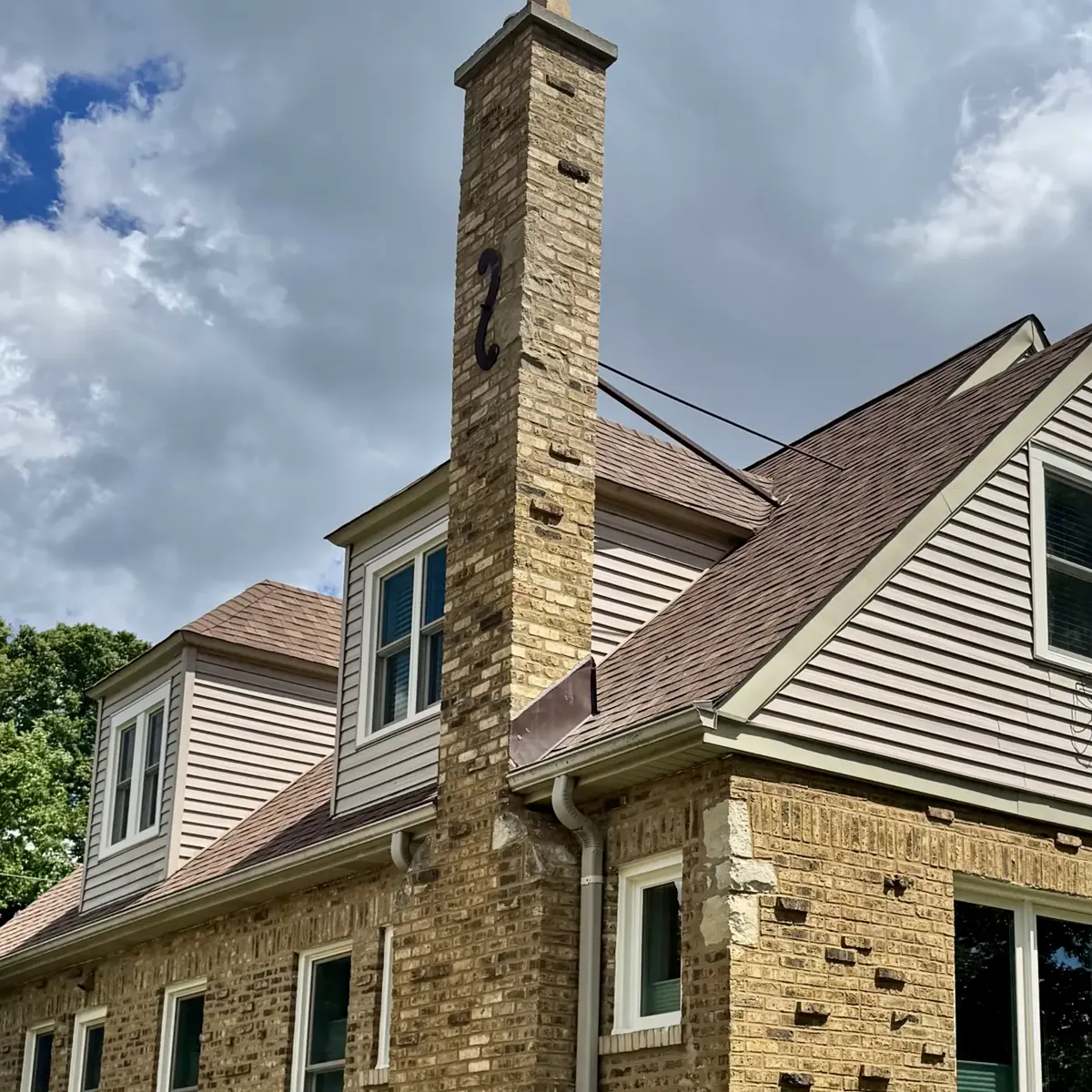 Yellow-brick Chicago bungalow with a freshly tuckpointed chimney rising above the roofline — Star Tuckpointing