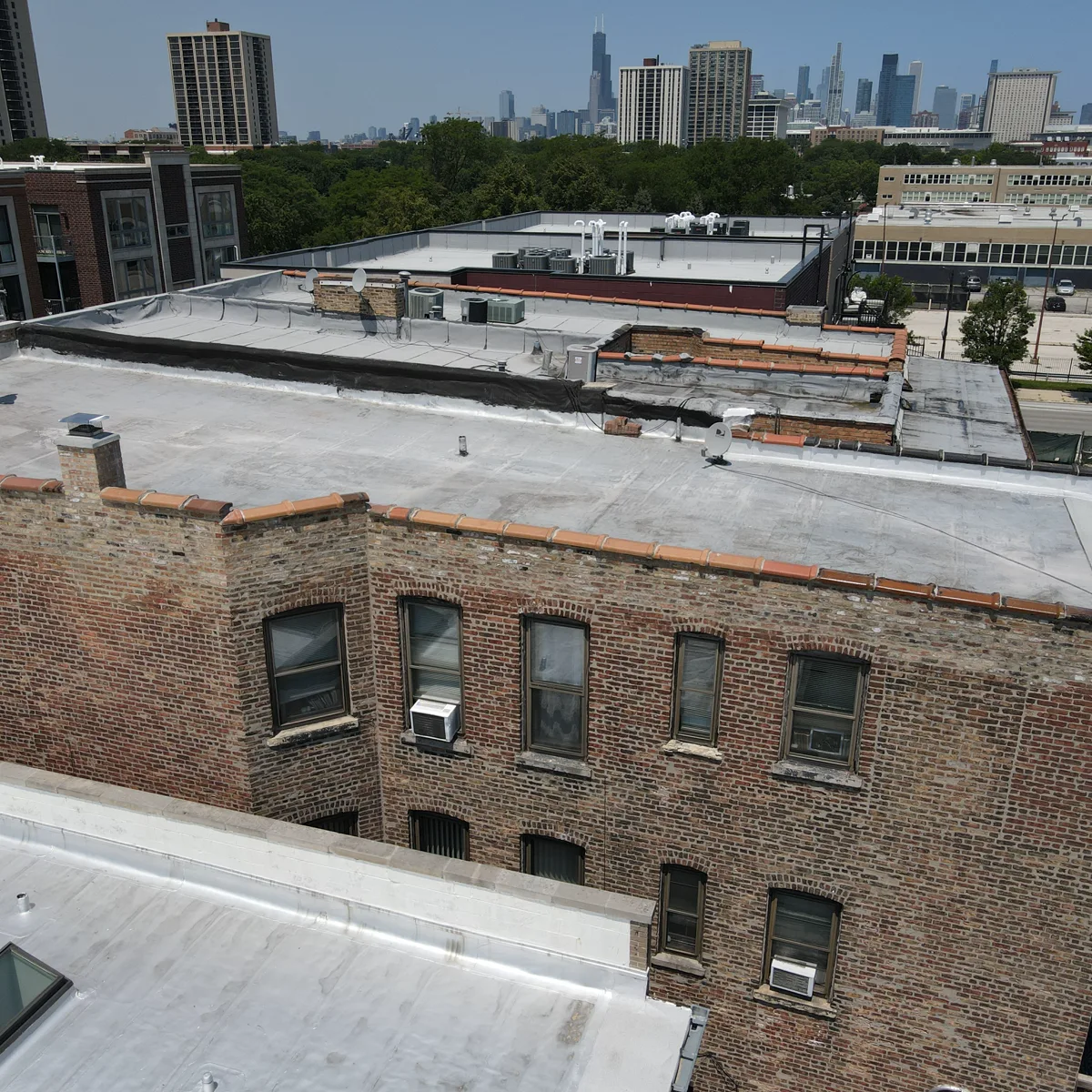 Completed Chicago brick parapet wall restoration with new coping stones and Chicago skyline in the background