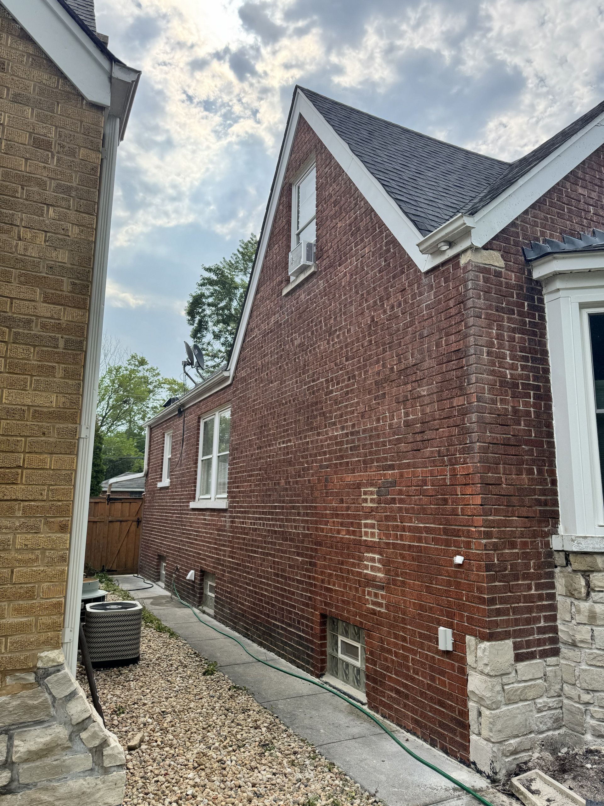Exterior brick wall before tuckpointing, with worn mortar joints along the side elevation